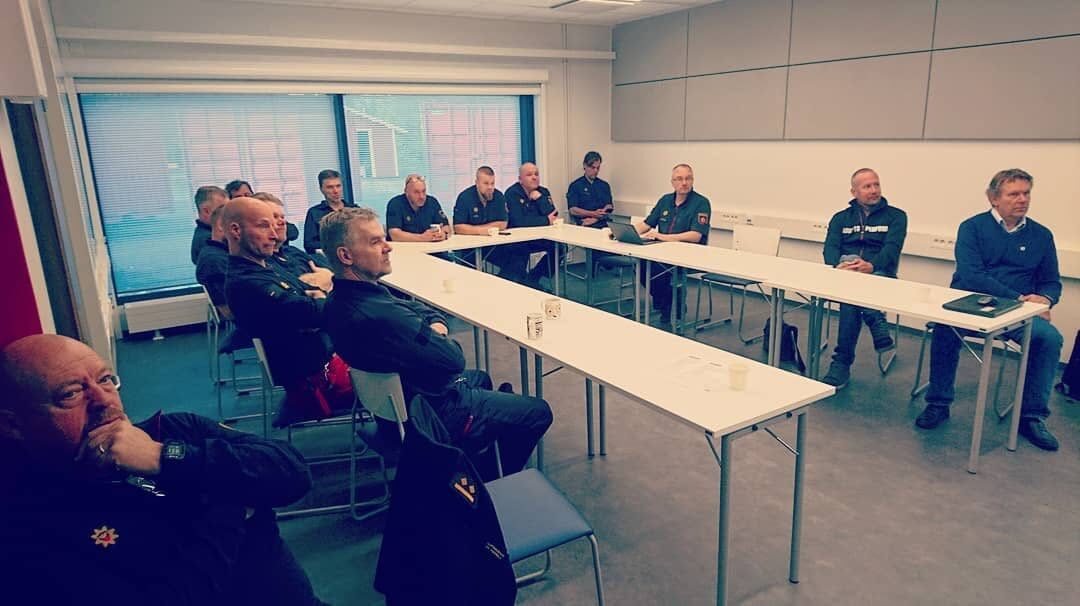 Ihmisiä istumassa kokoustilassa pitkien pöytien ääressä.